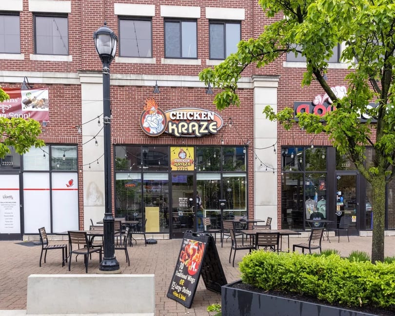 Chicken Kraze restaurant exterior with outdoor seating, brick facade, and a promotional sign for wings and shrimp.